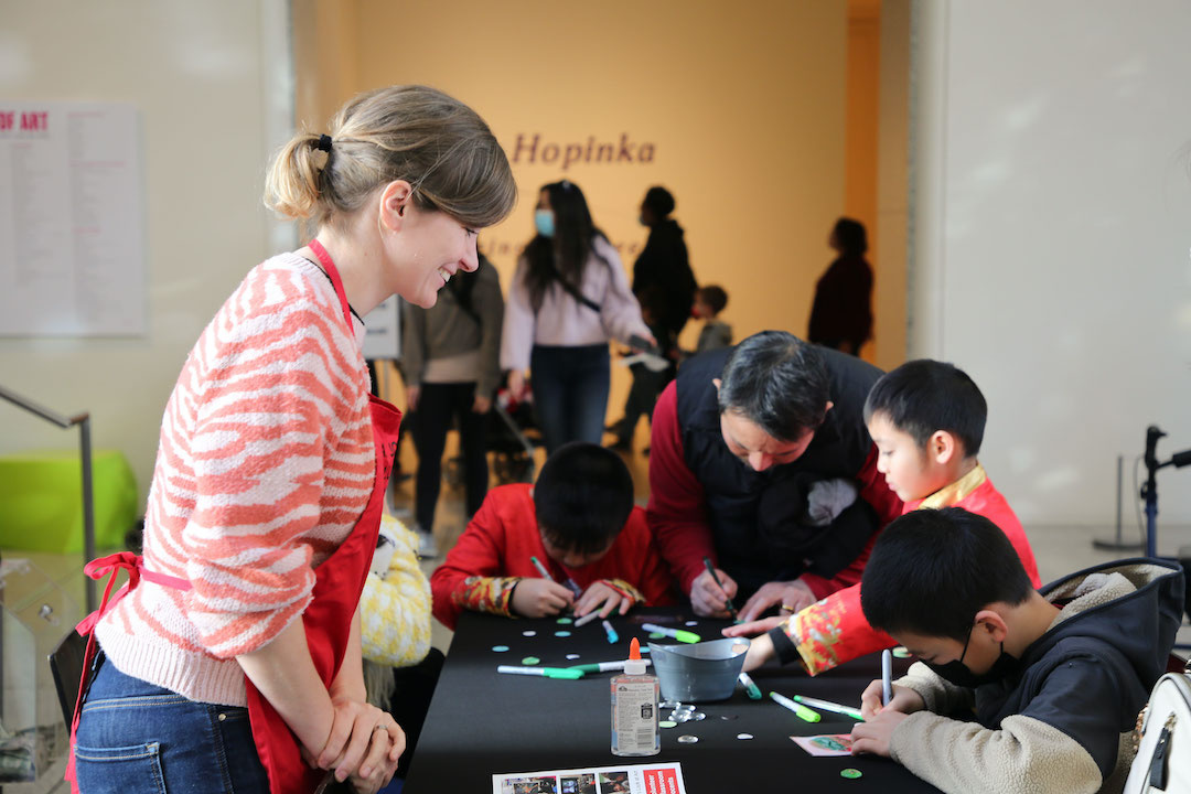 woman facilitating an art activity with young children wearing red