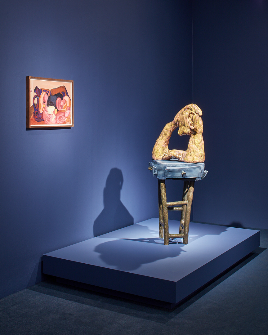 A dark blue gallery with spotlighted abstract painting on the wall and a pedestal with a ceramic sculpture on a ceramic stool. There is a large shadow on the wall from the sculpture.