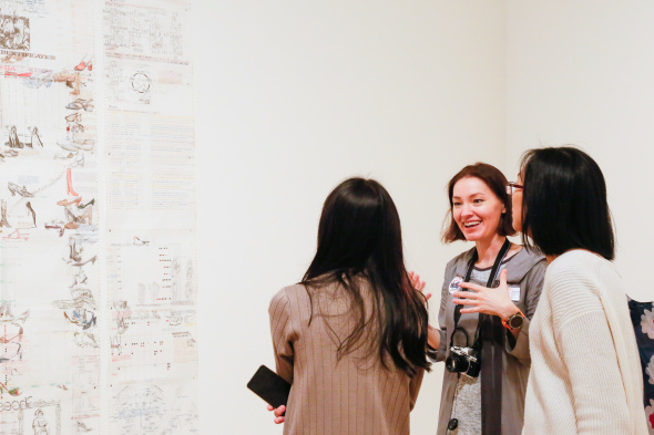 Three women interact while looking at art.